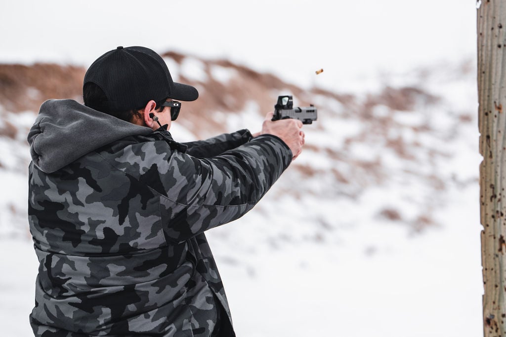 Shooter firing an Atlas Gunworks Athena v2 on a snowy range — real photo, unaltered